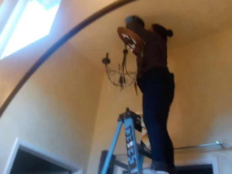 Electrician installing a chandelier in a Broken Bow residence